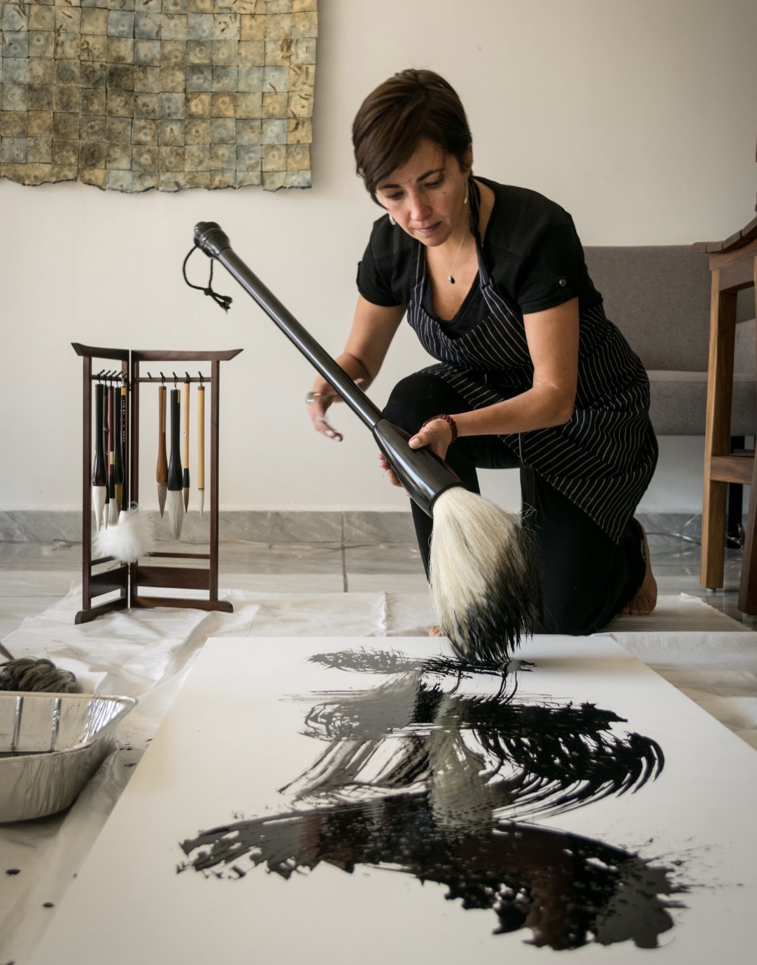 Gabriela Sánchez pintando un gran trazo con un pincel zen en su taller